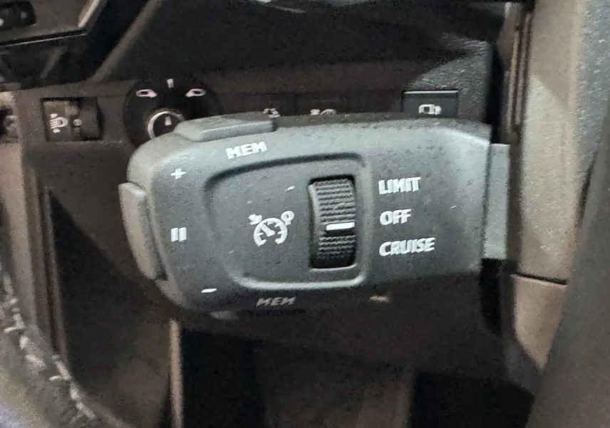 Gros plan sur la commande de régulateur de vitesse du DS7 Crossback E-TENSE 225 Bastille+ en intérieur noir.