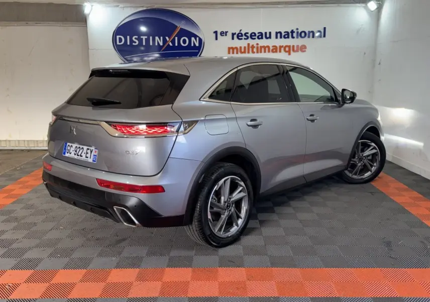 Vue 3/4 arrière droit du DS7 Crossback E-TENSE 225 Bastille+ gris foncé, feux arrière allumés et jantes alliage visibles.