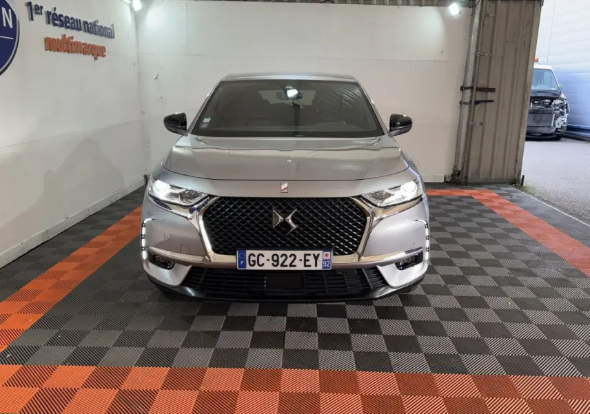 Vue frontale d’un DS7 Crossback E-TENSE 225 Bastille+ gris foncé avec calandre noire et phares allumés.