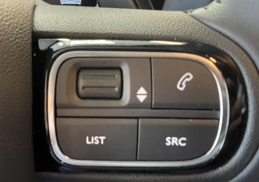Gros plan sur les commandes noires du volant avec boutons de téléphone et réglages audio du Citroën C5 Aircross hybride 2025.