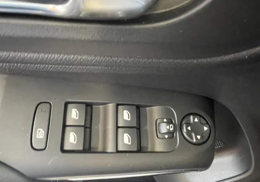 Gros plan sur les commandes de lève-vitres et réglage des rétroviseurs côté conducteur d'une Citroën C5 Aircross hybride bleu foncé.