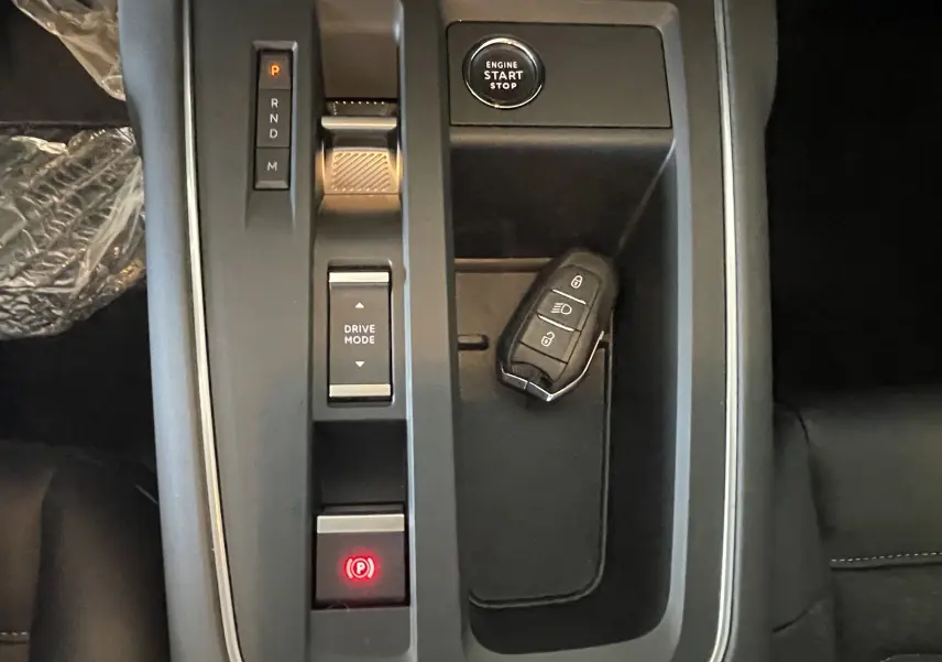 Vue rapprochée de la console centrale du Citroën C5 Aircross hybride 2025 avec bouton start/stop et clé posée.