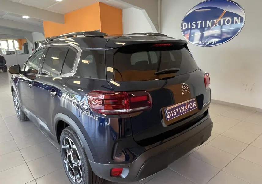 Vue 3/4 arrière droite du Citroën C5 Aircross hybride 2025 bleu foncé avec jantes alliage 18 pouces biton en showroom.