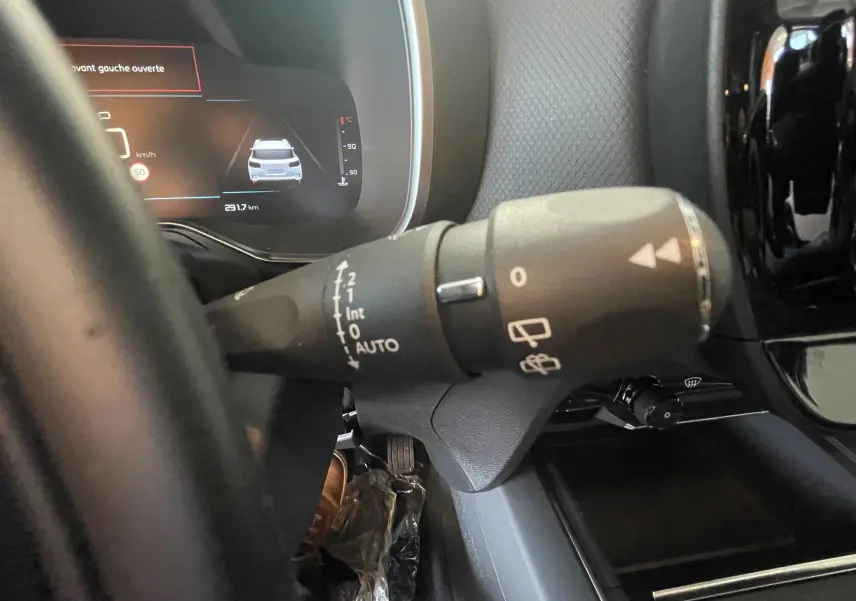Gros plan sur la commande d'essuie-glace à gauche du volant dans l'habitacle sombre du Citroën C5 Aircross hybride bleu foncé 2025.