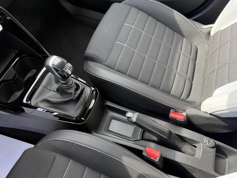 Vue rapprochée de l'intérieur de la Citroën C3 gris Mercury, montrant la boîte manuelle et les sièges en tissu noir.