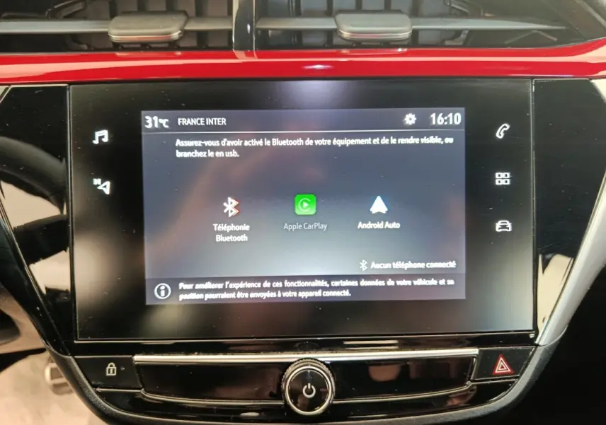 Écran tactile central de la console d’une Opel Corsa rouge, affichant les options Apple CarPlay et Android Auto.