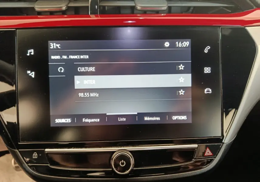 Écran tactile central de l’Opel Corsa rouge 2023 affichant la radio FM avec interface moderne et commandes tactiles.