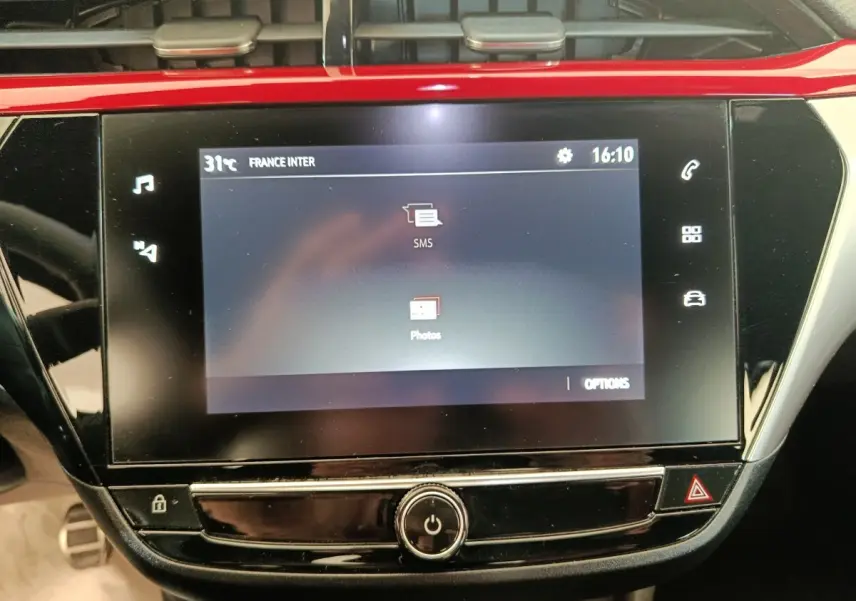 Écran tactile central de l’Opel Corsa rouge 2023 affichant les options SMS et Photos, vue de face rapprochée.