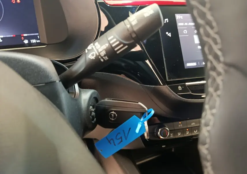 Vue intérieure rapprochée du volant cuir synthétique et de la clé dans le contact d’une Opel Corsa rouge 2023.