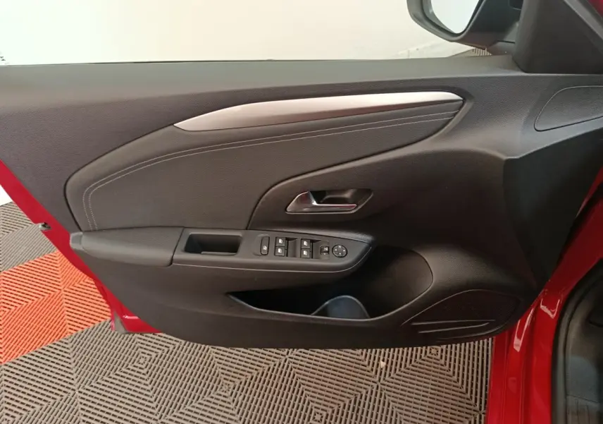 Vue intérieure côté gauche de la porte avant rouge d'une Opel Corsa 1.2 Turbo avec commandes électriques et garniture noire.