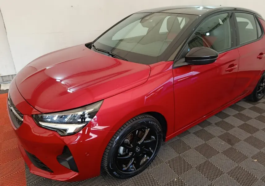 Vue 3/4 avant droite d’une Opel Corsa rouge 2023 avec toit noir et jantes noires brillantes.
