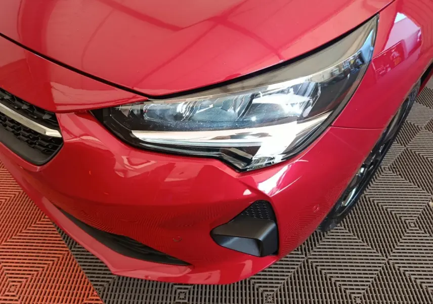 Gros plan sur l'avant droit rouge vif de l'Opel Corsa 2023, mettant en valeur le phare LED et la calandre.