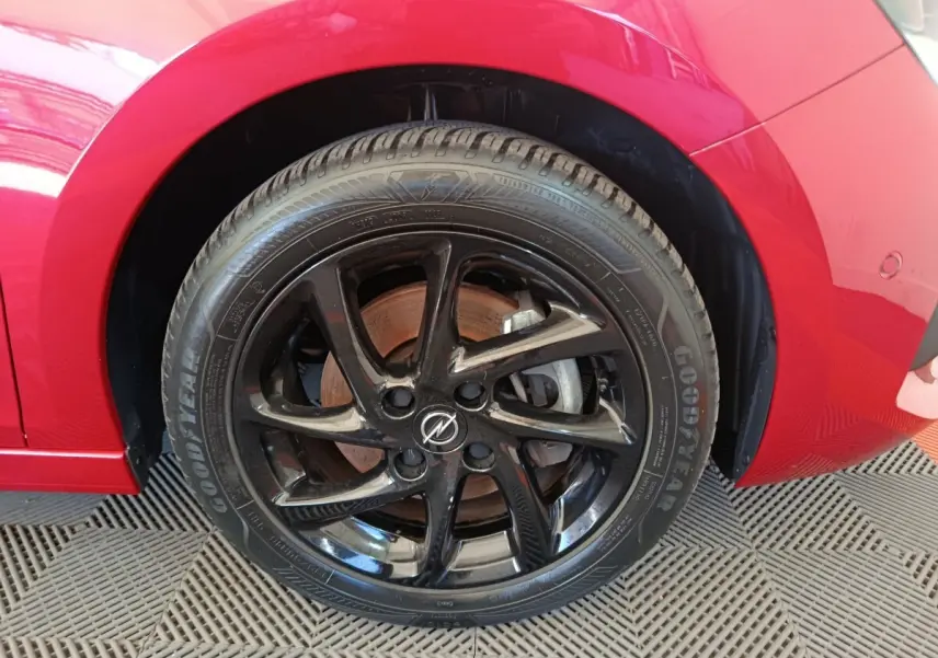 Gros plan sur la roue avant droite noire brillante d'une Opel Corsa rouge 2023, avec pneu Goodyear visible.