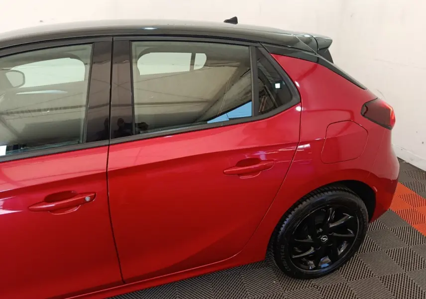 Vue latérale droite d'une Opel Corsa rouge 2023 avec toit noir et jantes noires brillantes.
