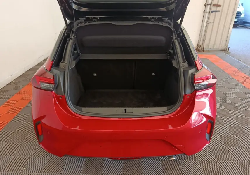 Vue arrière d'une Opel Corsa rouge 2023 avec coffre ouvert montrant l'espace de chargement vide.