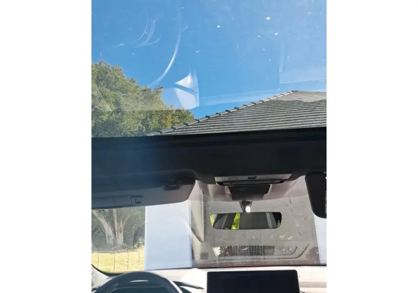 Vue intérieure du toit ouvrant panoramique et tableau de bord du Nissan Qashqai 2024 rouge foncé Tekna.