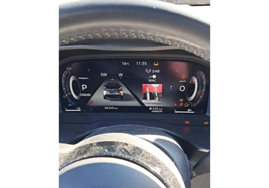 Vue rapprochée du tableau de bord numérique du Nissan Qashqai 2024 rouge foncé, affichant les informations de conduite et médias.