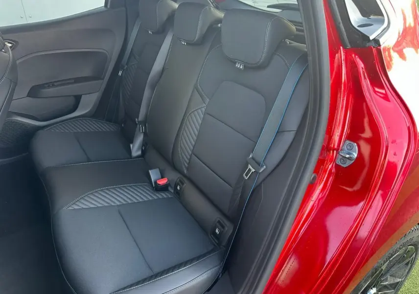 Vue côté droit sur la banquette arrière noire avec surpiqûres bleues d'une Renault Clio V rouge flamme.