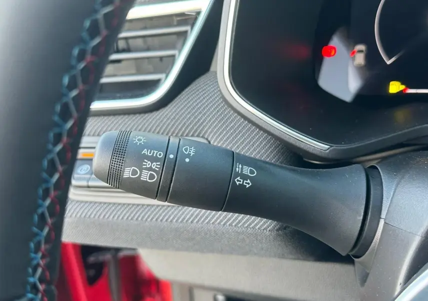 Gros plan sur la commande des feux et clignotants à gauche du volant d'une Renault Clio V rouge flamme metal.