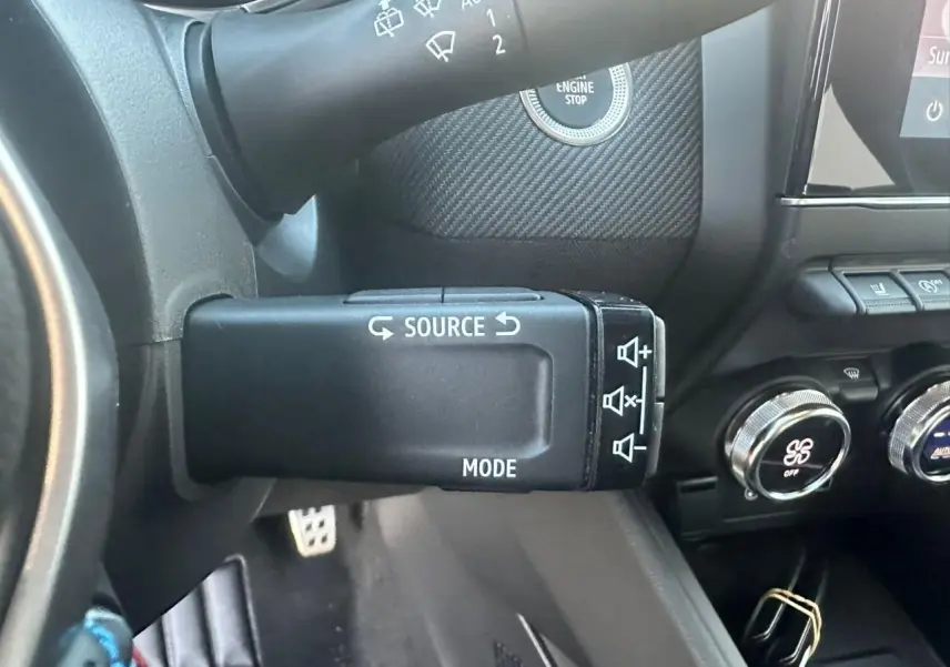 Gros plan sur la commande multimédia au volant de la Renault Clio V Esprit Alpine, intérieur noir avec détails argentés.