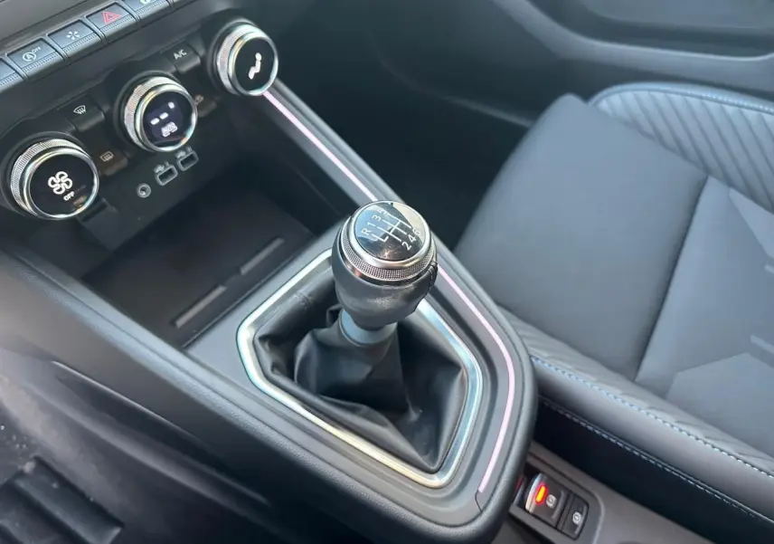 Gros plan sur levier de vitesse manuel et console centrale noire avec surpiqûres bleues dans Renault Clio V Esprit Alpine.