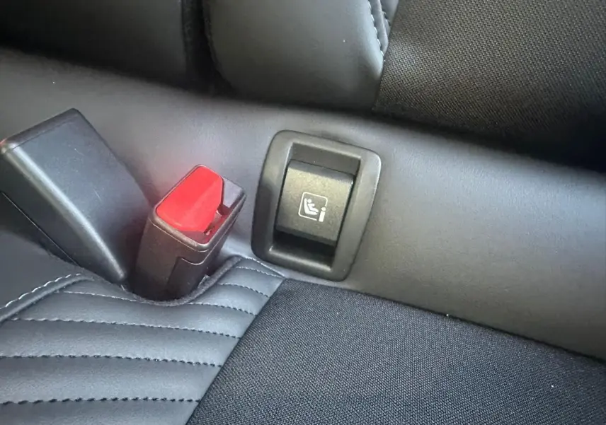 Gros plan sur la fixation ISOFIX et la boucle de ceinture rouge sur la banquette arrière noire de la Renault Clio V Esprit Alpine.