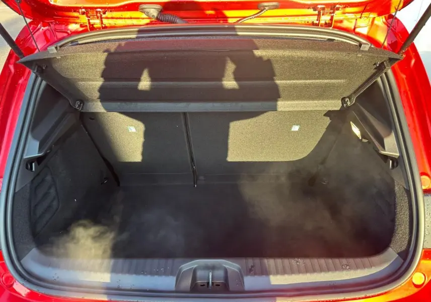 Coffre ouvert vu de dessus d'une Renault Clio rouge flamme métal, montrant l'espace de chargement intérieur.
