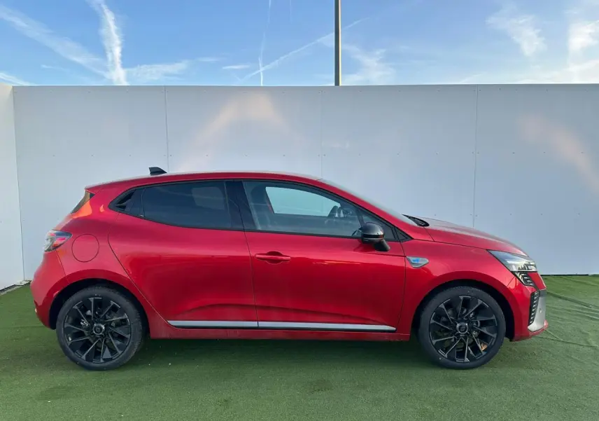 Profil droit d'une Renault Clio V rouge flamme métal avec jantes alliage noires et vitres surteintées.