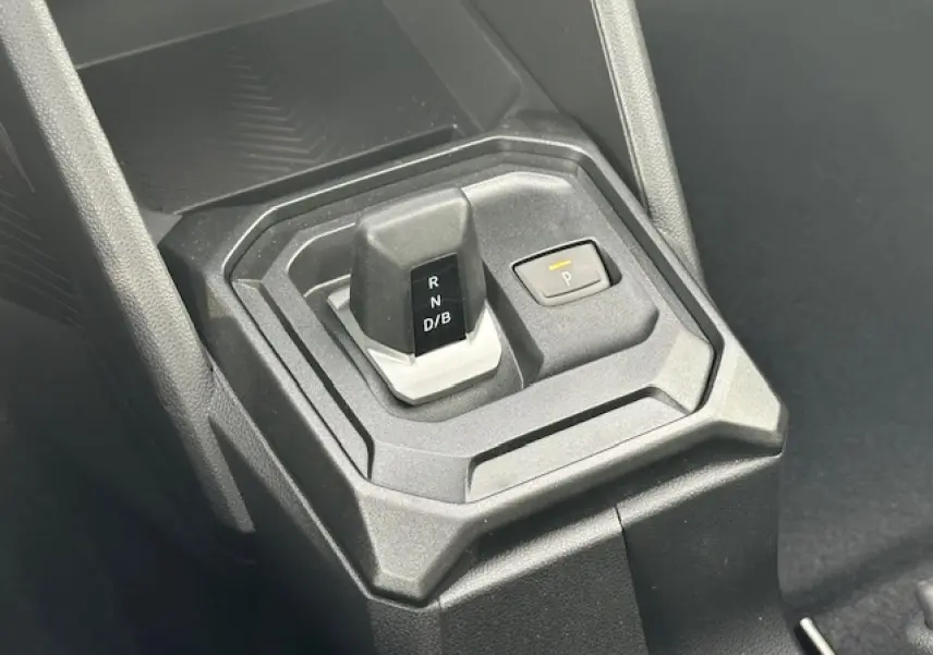 Le levier de vitesses automatique et bouton de parking du Dacia Duster III 1.6 Hybrid 140 en intérieur noir.