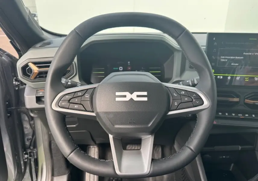 Volant soft feel noir avec commandes intégrées du Dacia Duster III 1.6 Hybrid 140 gris schiste, vue intérieure frontale.
