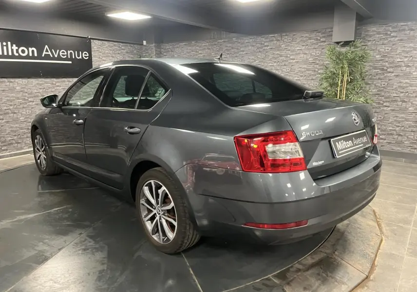 Vue 3/4 arrière droite d'une Skoda Octavia gris métallisé avec jantes alliage 17 pouces en intérieur showroom.