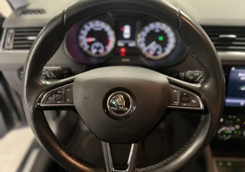 Volant cuir noir de Skoda Octavia 2020 avec commandes intégrées, tableau de bord numérique flou en arrière-plan.