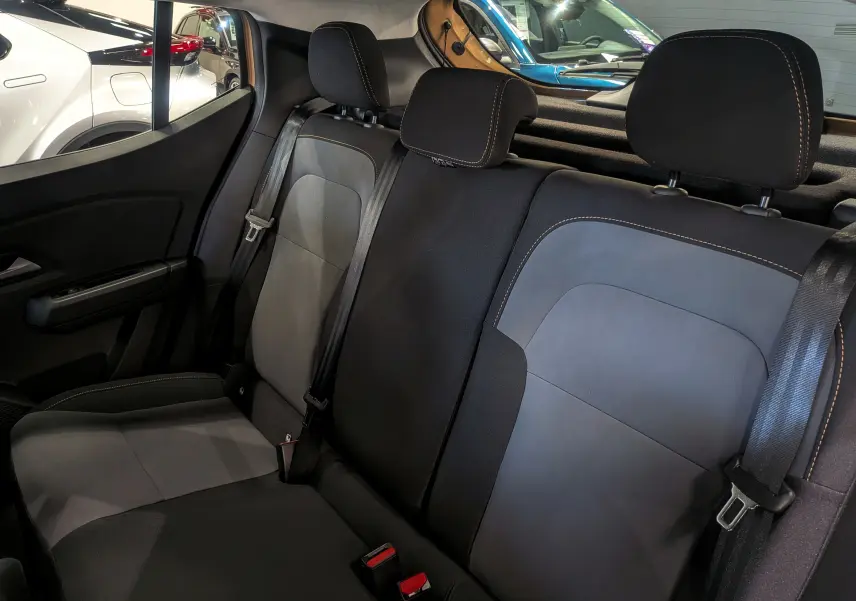 Vue intérieure sur les sièges arrière en tissu noir et gris du Dacia Sandero Stepway 2025, avec ceintures de sécurité visibles.