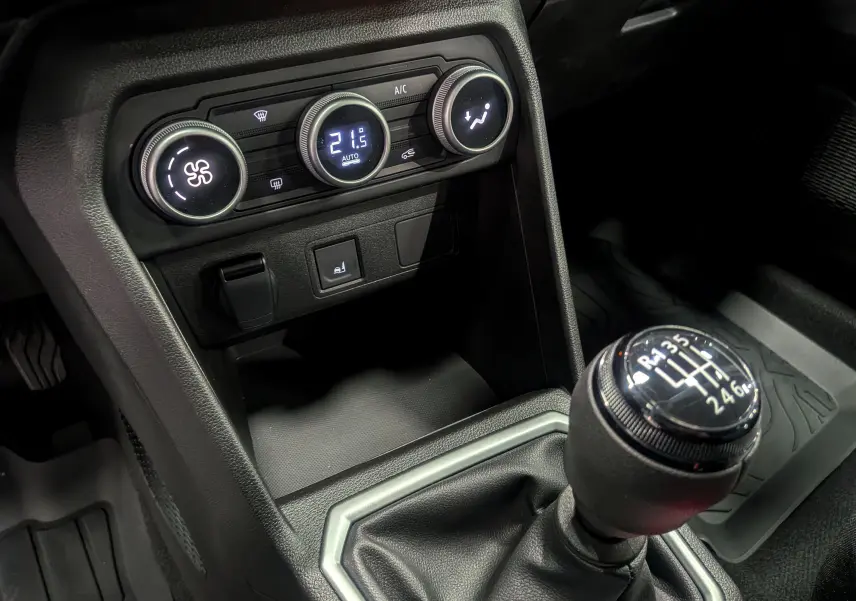 Gros plan sur la console centrale de la Dacia Sandero Stepway beige Safari 2025, avec la commande de climatisation et le levier de vitesses manuel.