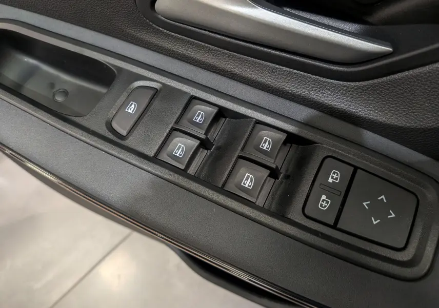 Gros plan sur les commandes électriques des vitres et des rétroviseurs sur la porte côté conducteur d'une Dacia Sandero Stepway beige Safari.