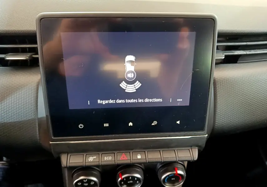 Écran tactile central affichant l'alerte de capteurs de recul dans l'habitacle d'une Renault Clio Business blanc.