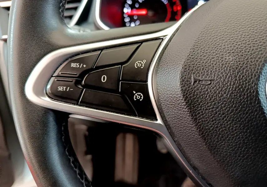 Gros plan sur le volant cuir noir de la Renault Clio Business, montrant les commandes du régulateur de vitesse à gauche.