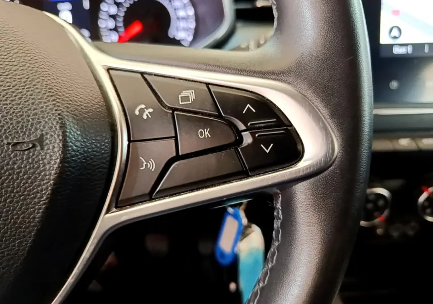 Gros plan sur les commandes multifonctions du volant en cuir noir de la Renault Clio Business Blue dCi 85 blanche de 2020.