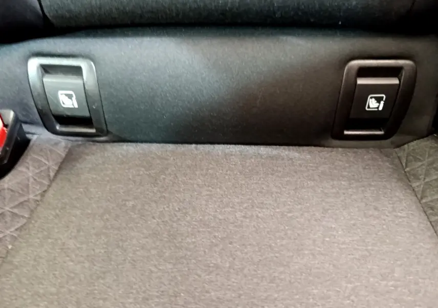 Gros plan sur la banquette arrière et les commandes d'abaissement des sièges dans le coffre de la Renault Clio Business blanche.