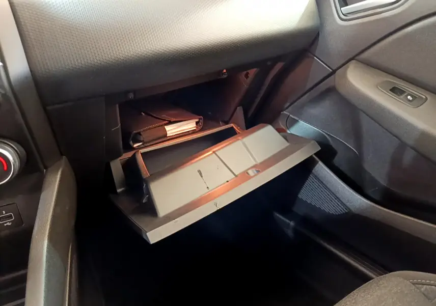 Gant de boîte à gants ouvert côté passager dans l'habitacle noir de la Renault Clio Business Blue dCi 85 blanche.