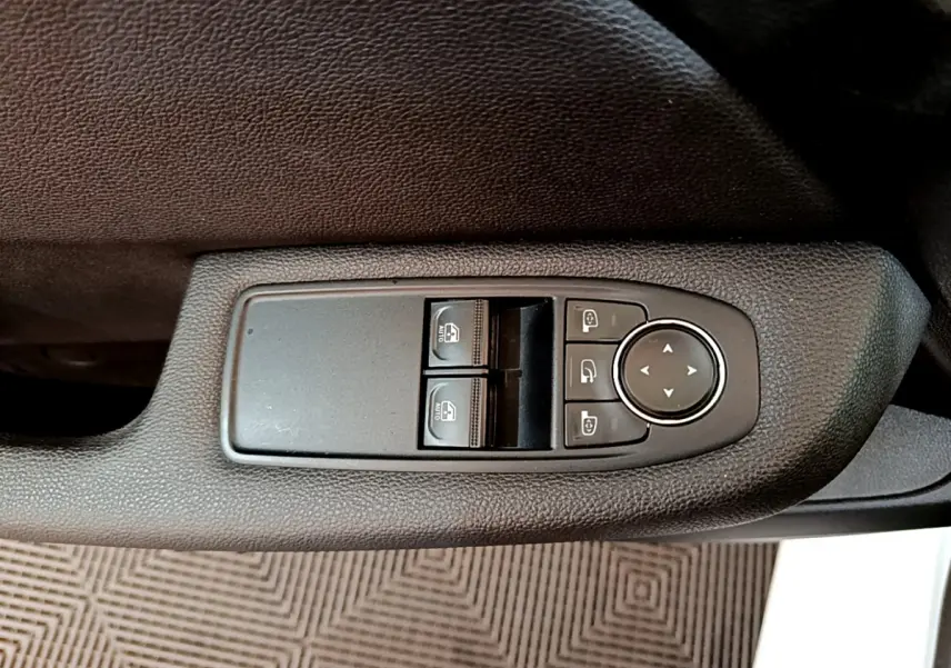 Gros plan sur les commandes de lève-vitres et réglages des rétroviseurs côté conducteur d'une Renault Clio blanche 2020