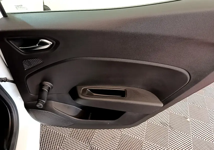 Vue intérieure du panneau de porte côté gauche de la Renault Clio Business blanc, avec manivelle de vitre manuelle.