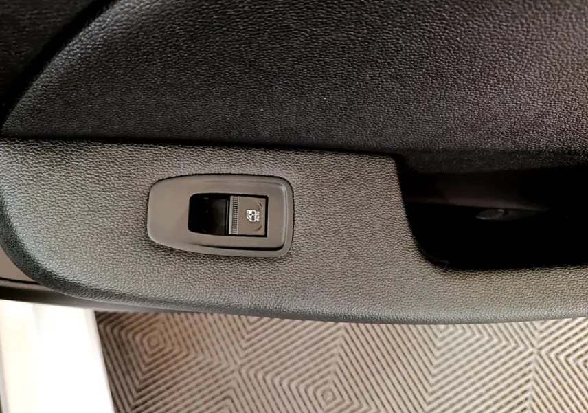 Bouton de commande de lève-vitre sur la porte intérieure noire côté conducteur d'une Renault Clio Business 2020 blanche.