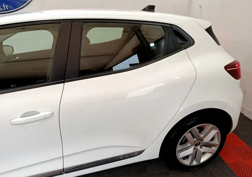Vue de profil côté gauche d'une Renault Clio blanche avec jantes alliage et poignées de porte intégrées.