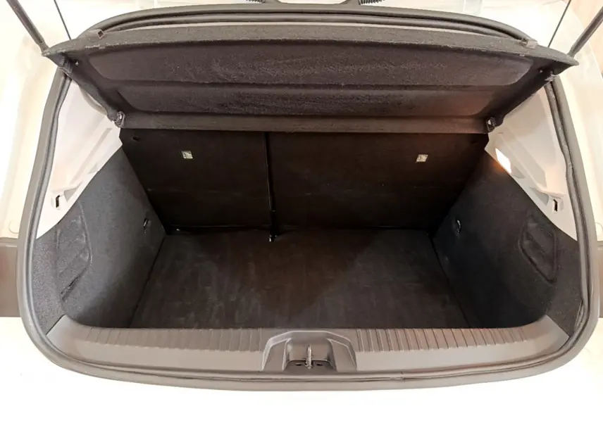 Coffre ouvert vu de l'arrière d'une Renault Clio Business Blue dCi 85 blanche, intérieur noir et espace de rangement visible.