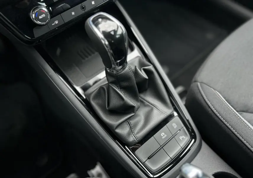 Gros plan sur la console centrale du Skoda Kamiq 2025, montrant le levier de vitesse automatique en cuir noir et les boutons de contrôle.