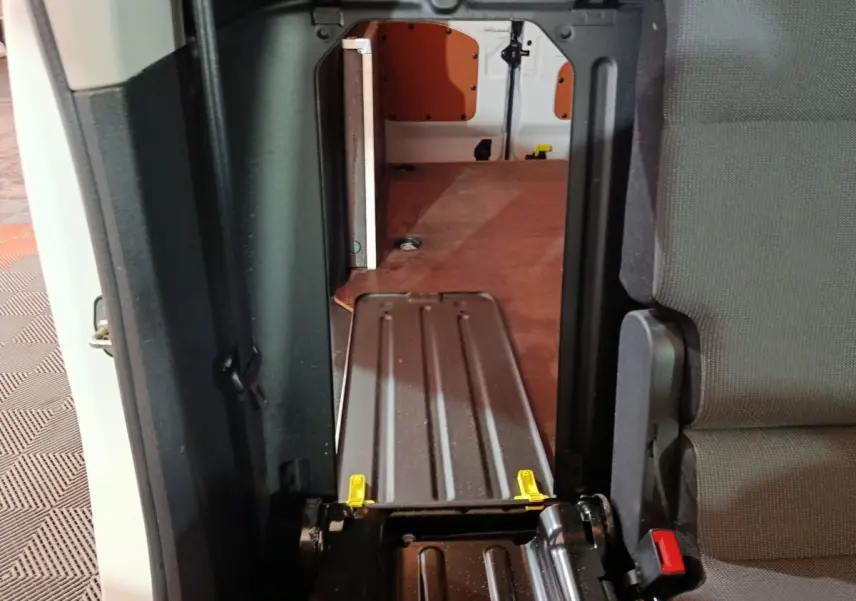 Vue intérieure du passage entre cabine et espace de chargement du Citroën Berlingo blanc, avec cloison pleine visible.