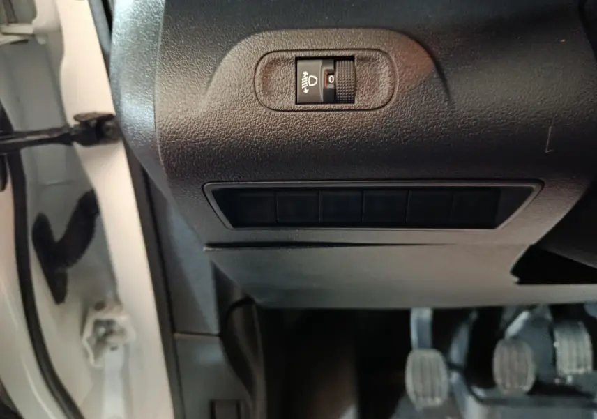 Détail du tableau de bord noir côté gauche avec réglage manuel des phares sur Citroën Berlingo blanc 2021.