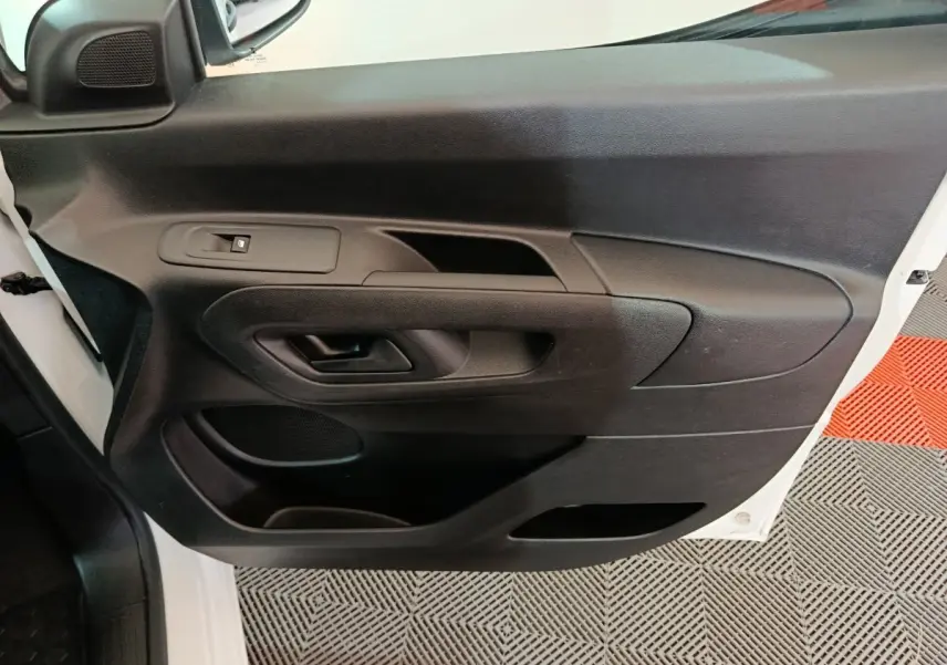 Vue rapprochée de la porte avant gauche noire du Citroën Berlingo blanc, montrant la poignée et les commandes de vitre.