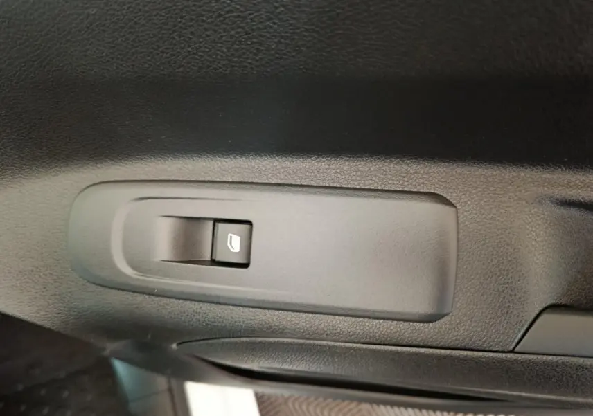 Bouton de commande de lève-vitre noir sur la porte intérieure d'un Citroën Berlingo blanc 2021.